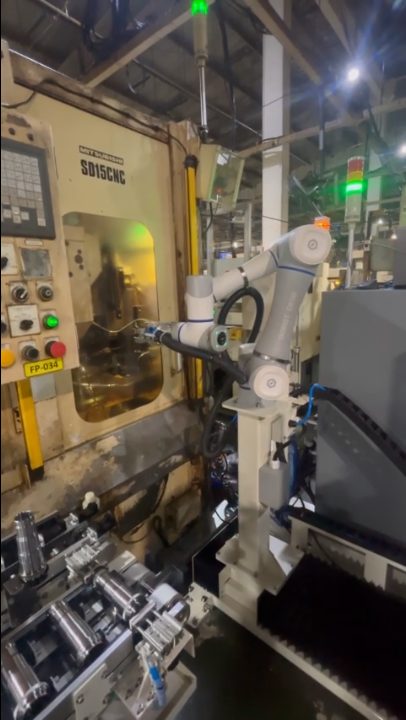 Robot bố trí cạnh máy CNC và khay chứa phôi dạng trụ